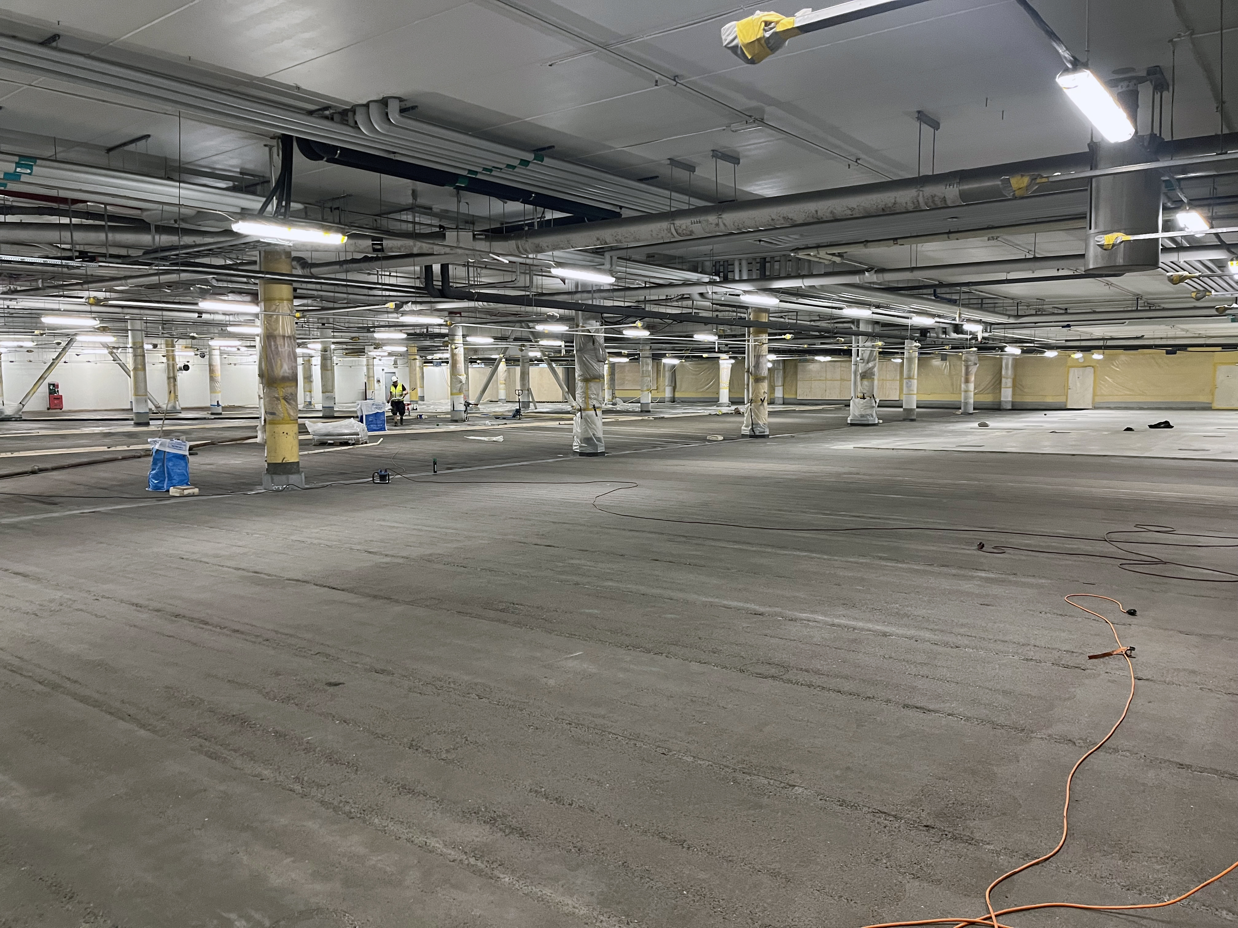 Parkeringsgarage med synliga rör och kablar i taket.