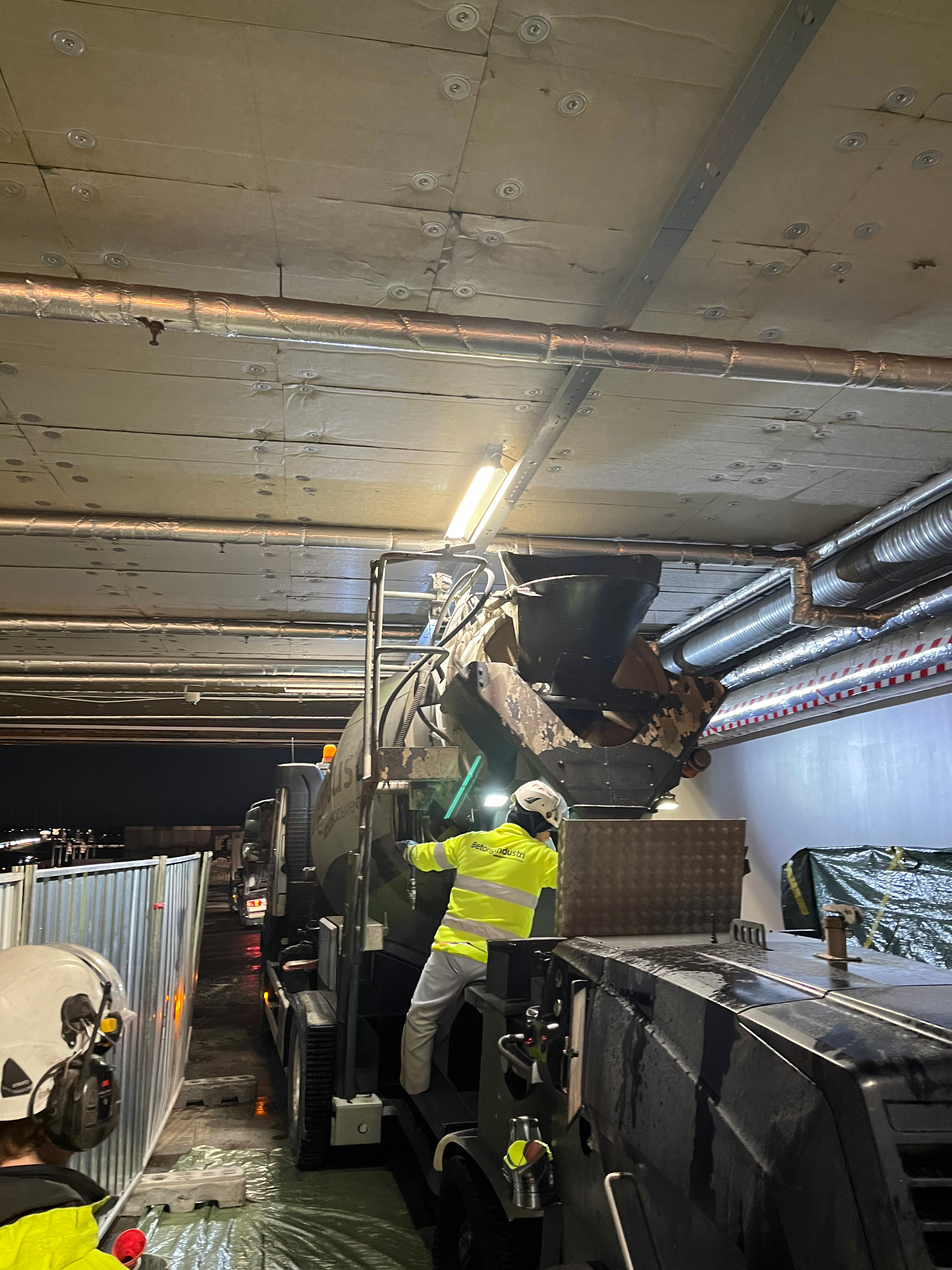 En arbetare i skyddsutrustning övervakar pumpning av betong.