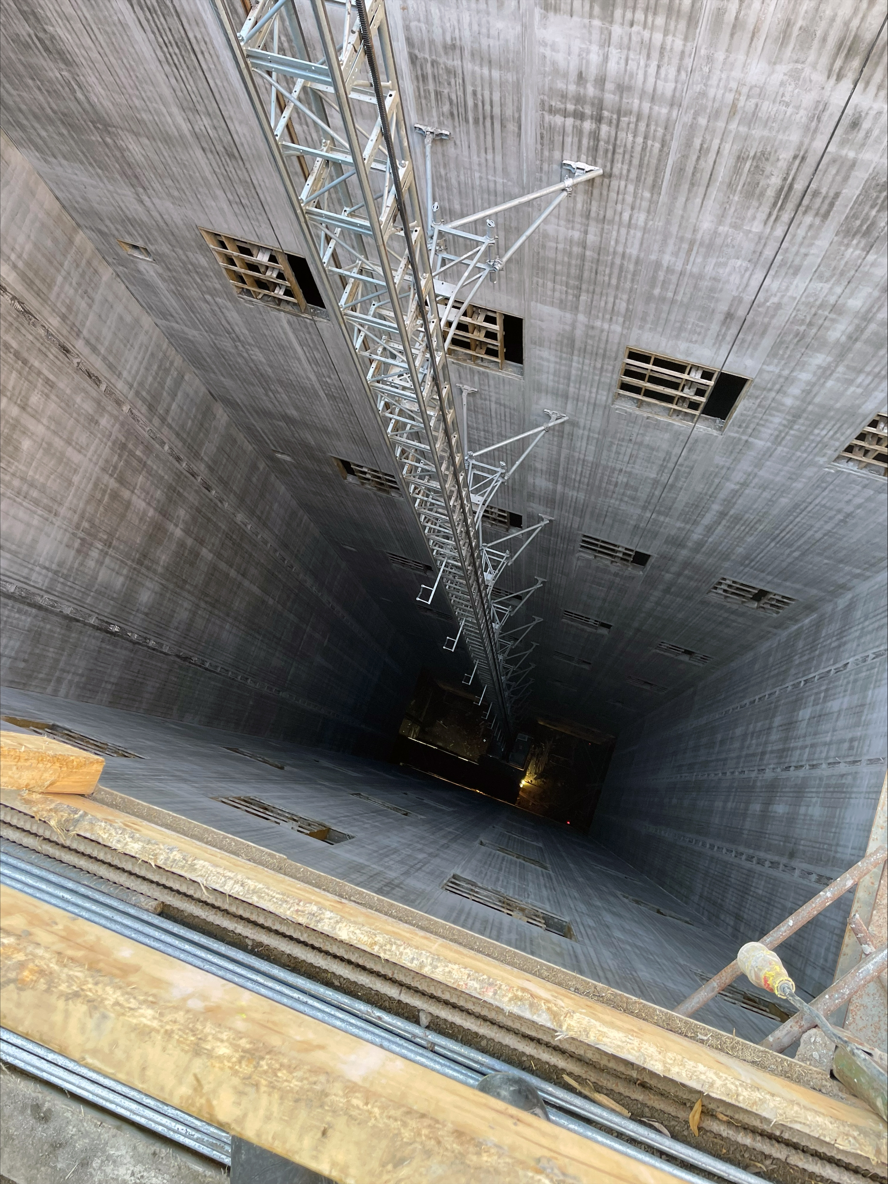 Vy från ovan av en djup hissschakt med metallstrukturer i mitten.