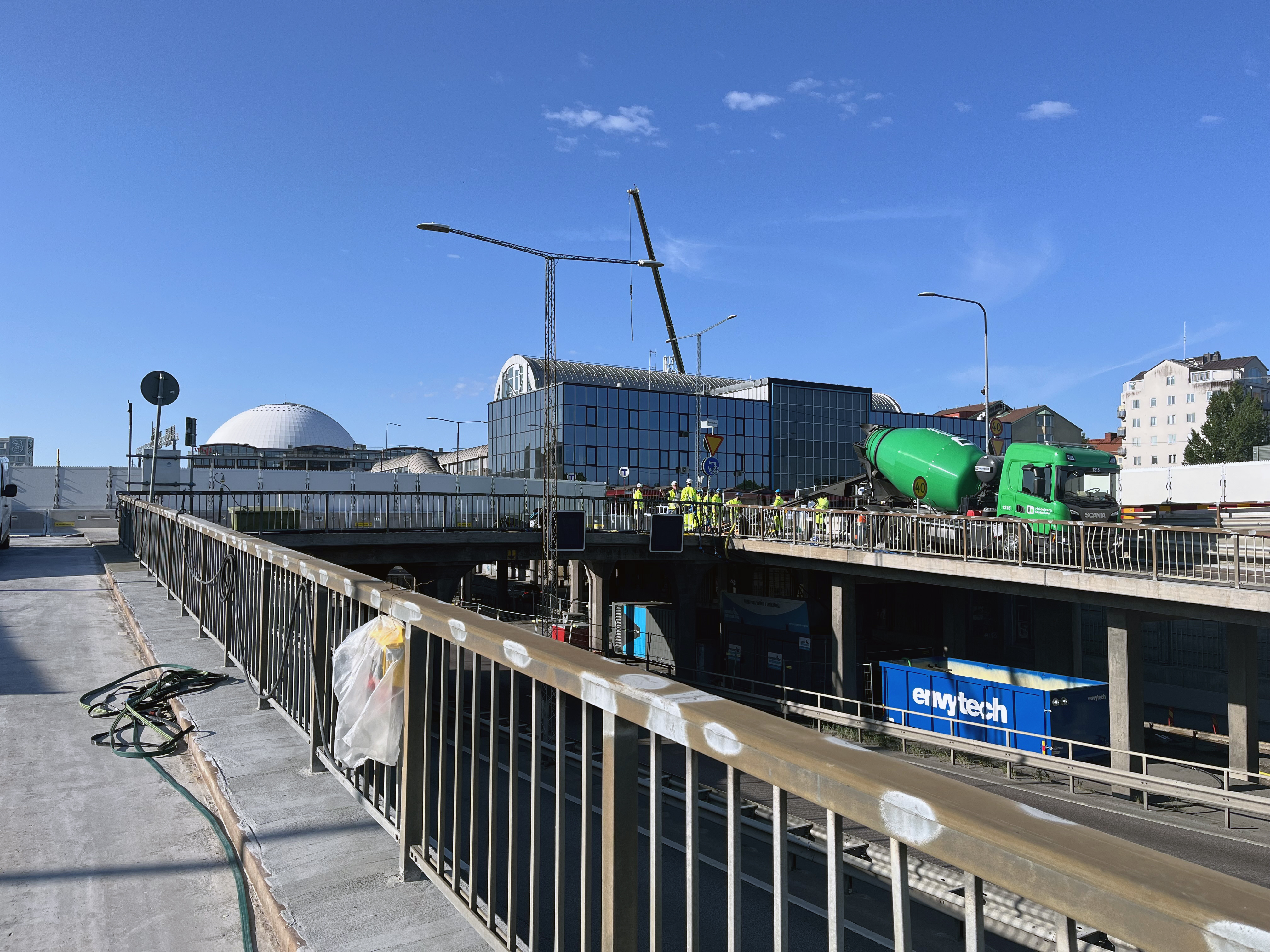En byggarbetsplats med kranar, byggmaterial och arbetare i en stadsmiljö.