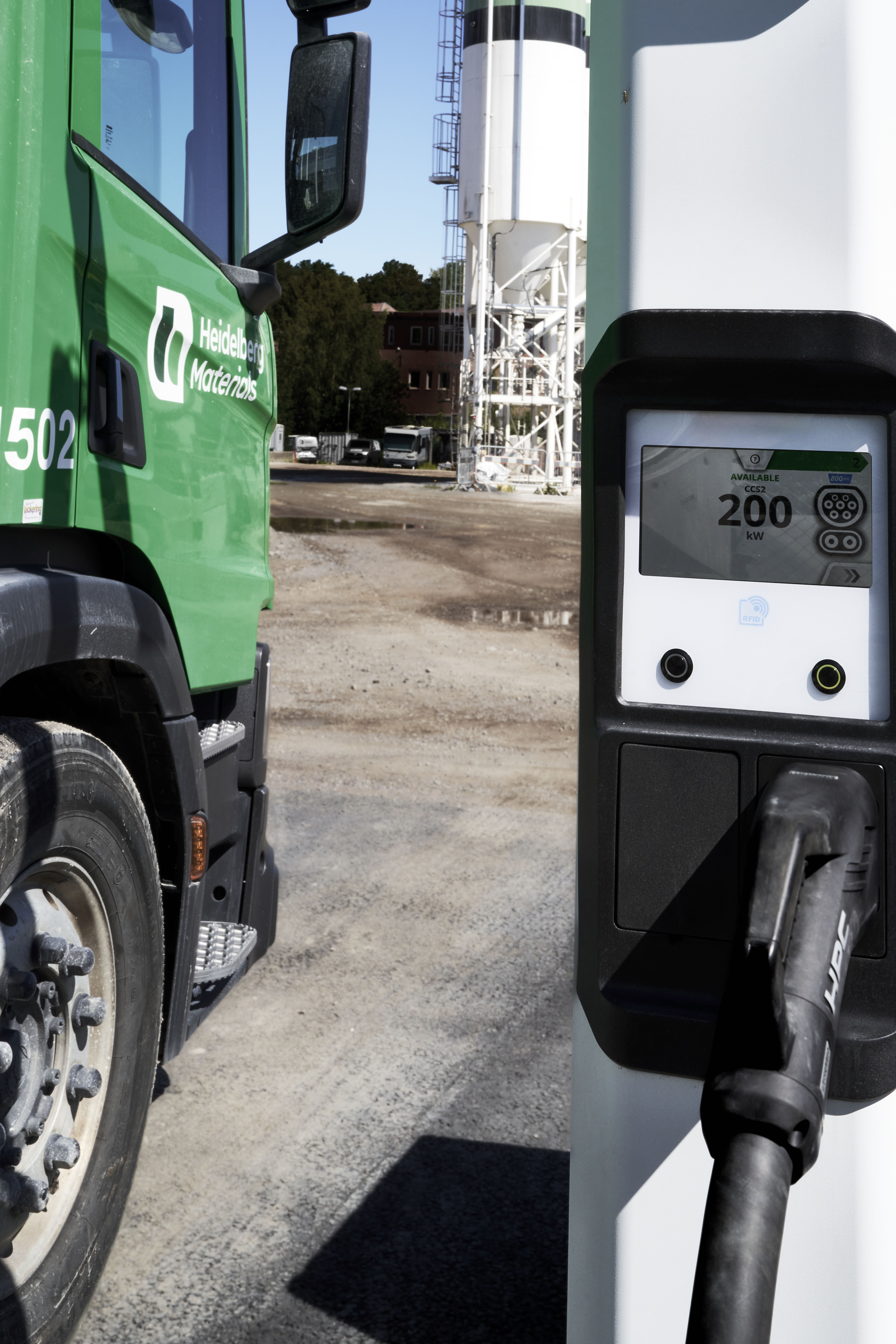 En grön betongbil vid en laddstation på ett industriområde, Ulvsunda.