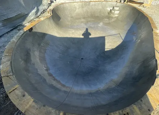 Skateramp i betong under konstruktion med en skugga av en person i centrum.