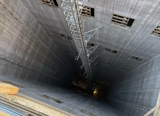 Vy från ovan av en djup hissschakt med metallstrukturer i mitten.