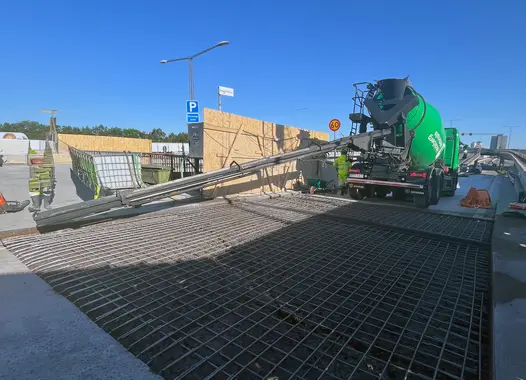 Betong levereras från en betonglastbil till en byggarbetsplats med armeringsjärn i fokus.